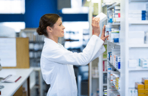 Stock photo of a pharmacist stocking medicine on shelves.